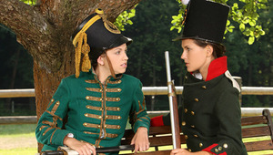 Juliette and Deny - Stunning teen Deny, darker hair, is sitting on a bench dressed in antique army clothes, when luscious minx Juliette, green antique jacket approaches her. They are tired from reenacting historic battles, so Juliette sits beside Deny and